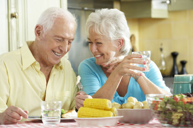 implant-supported-dentures-patients-eating Dental Implant Patients Smiling Together While Eating Dinner