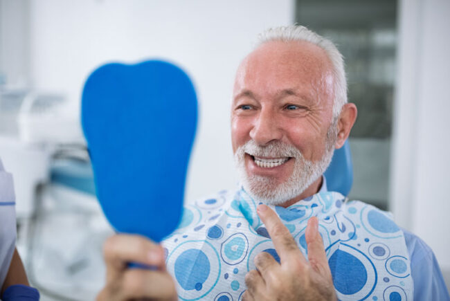 dental-implants-patient-smiling-after-procedure a dental patient smiling after successful dental implant surgery without anxiety
