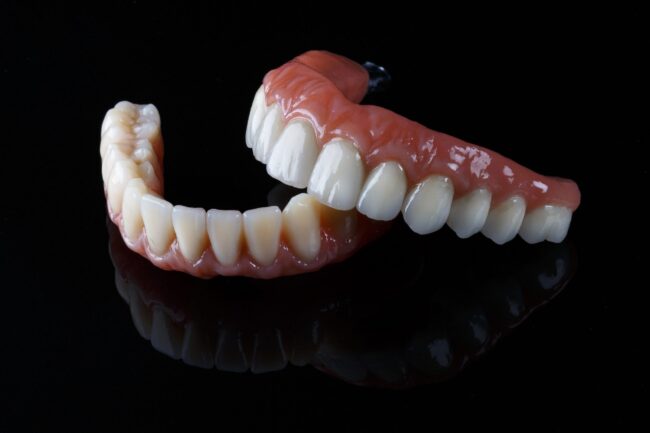 ceramic prosthesis with artificial gums, upper and lower jaw on black glass ceramic prosthesis with artificial gums, upper and lower jaw on black glass