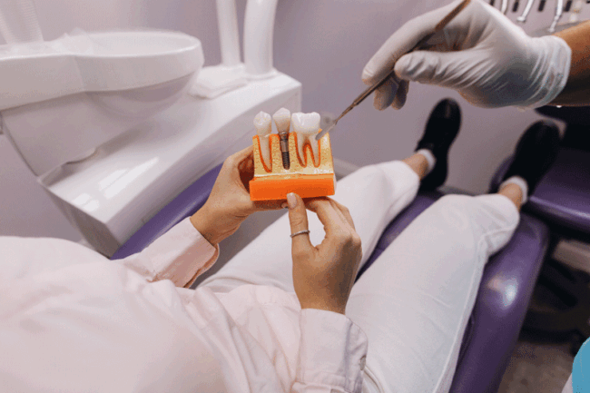 Implants2-24 Patient in chair holding a dental implant model with thew doctor giving information